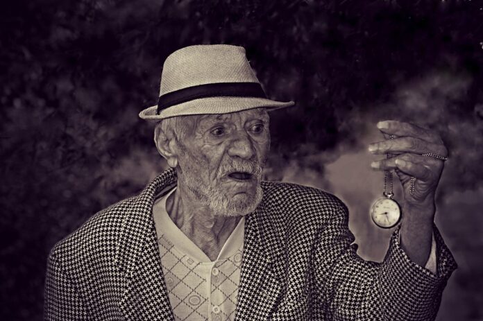 Uomo anziano sorregge un orologio da taschino, bellezza