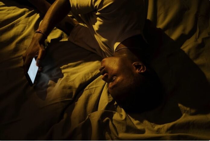 ragazzo a letto con il telefono in mano, insonnia
